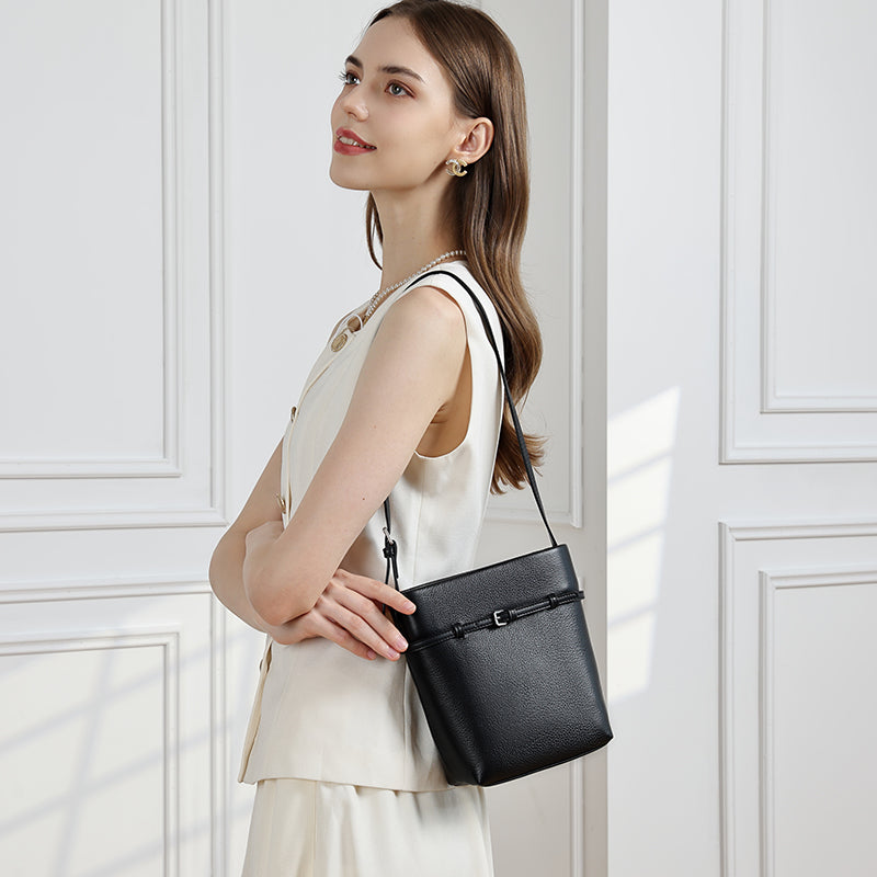 Woman in a cream outfit wearing a black bucket bag on her shoulder