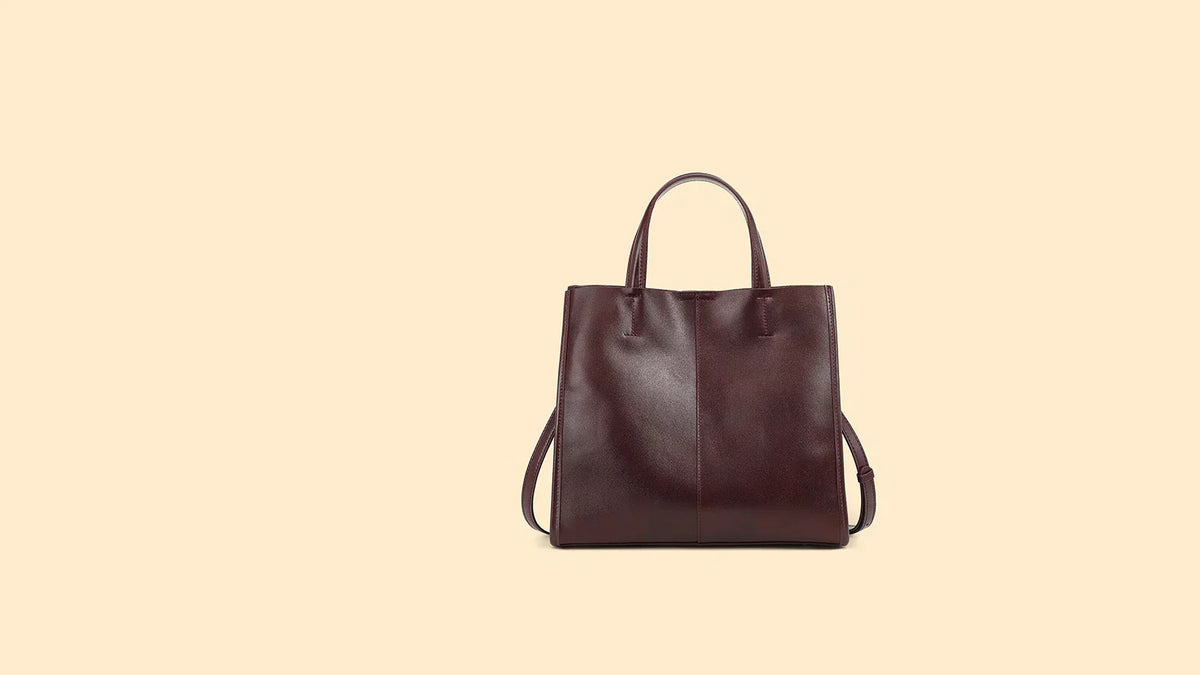 Cuirae coffee leather work tote on beige background showing structured shape and top handles