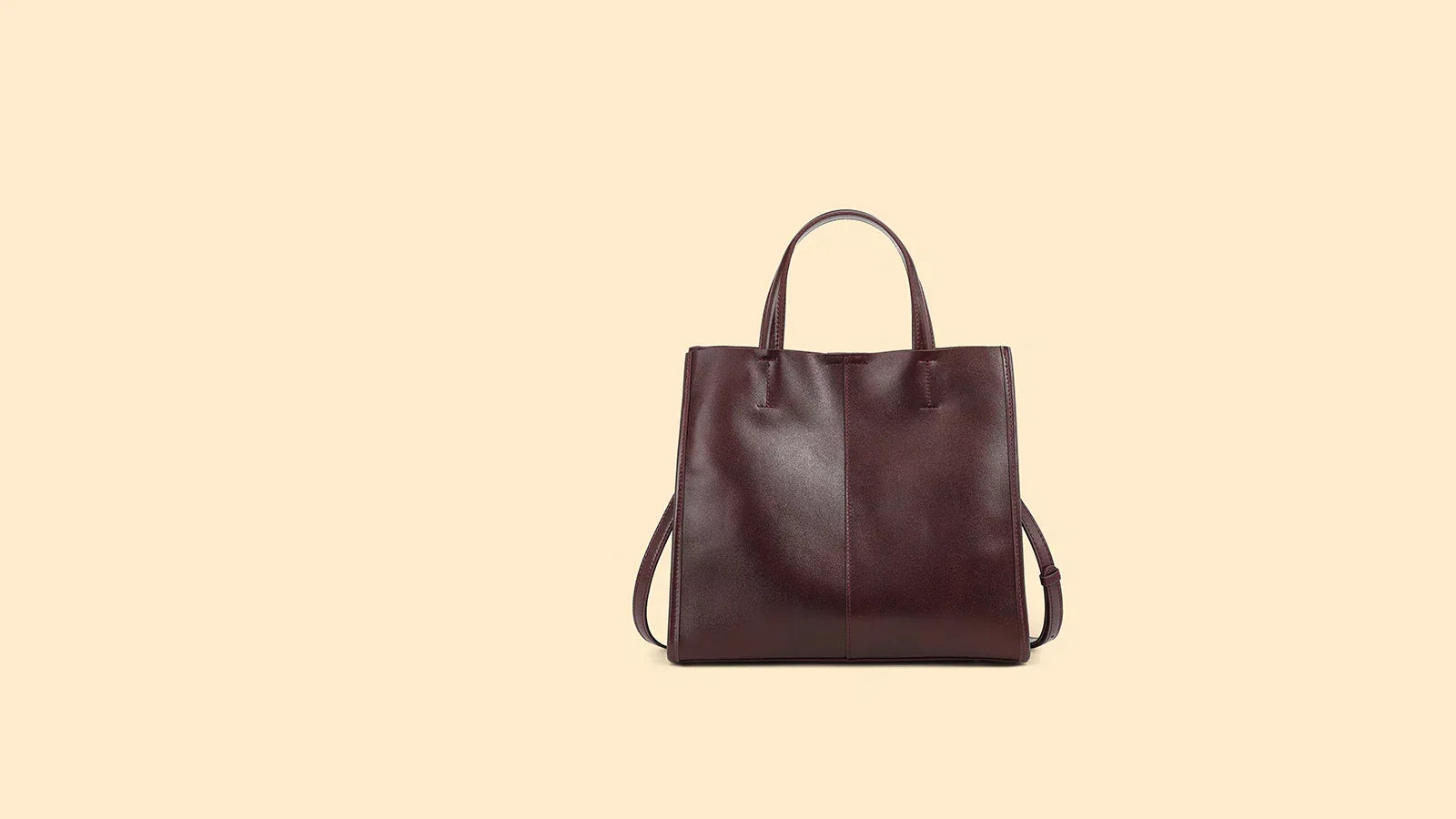 Cuirae coffee leather work tote on beige background showing structured shape and top handles