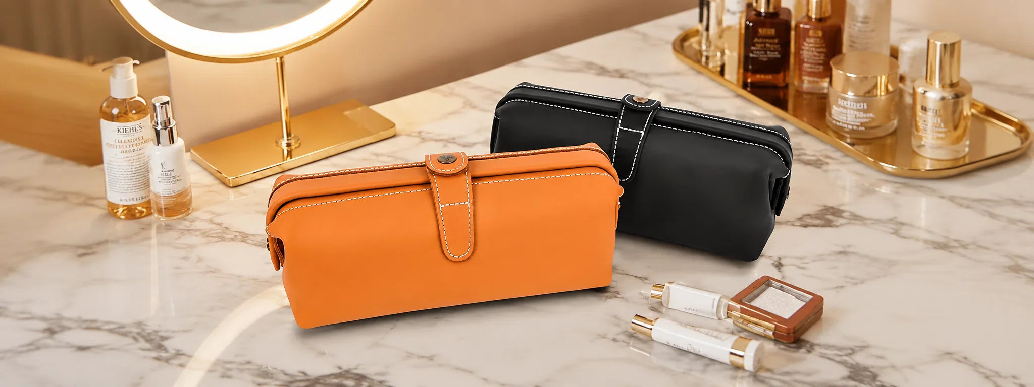 Explore the Cuirae collection of genuine leather makeup bags, showing an orange and a black bag on a marble vanity with skincare bottles.