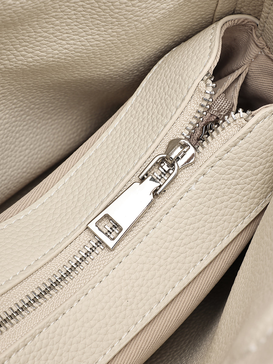 Close-up of the ivory bag's zipper and pebbled leather