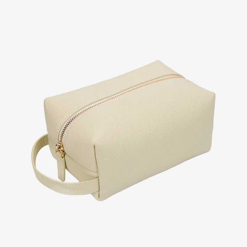 Cuirae beige pebbled genuine leather makeup bag with gold zipper and wrist strap, front angled view on white background