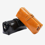 Cuirae black and brown glossy genuine leather makeup bags, two color variants stacked on white background with buckle closure