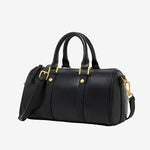 Cuirae black genuine leather barrel crossbody bag with gold hardware and detachable strap, side view on white background