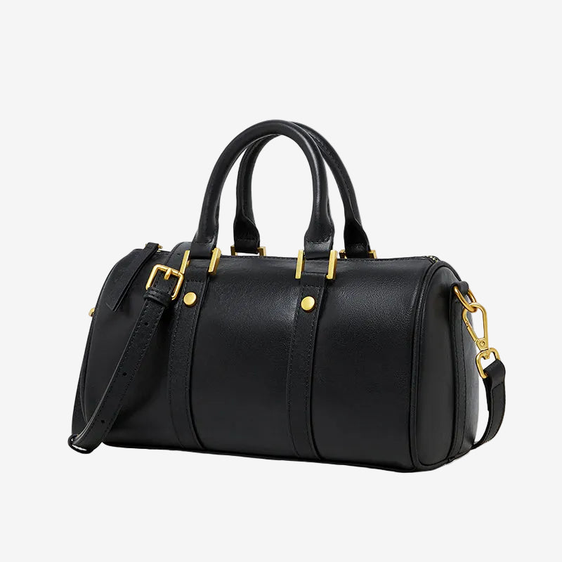 Cuirae black genuine leather barrel crossbody bag with gold hardware and detachable strap, side view on white background