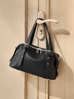 Cuirae black genuine leather bowling shoulder bag hanging on door handle, natural light showing double zipper closure