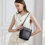Woman wearing Cuirae black genuine leather bucket bag on shoulder, side view showing adjustable strap