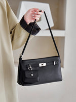 Model holding Cuirae black genuine leather crossbody bag by strap, front view showcasing pebbled texture and coin purse