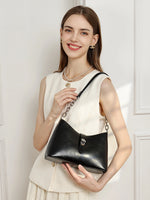 A smiling woman in a white outfit carrying the Cuirae black genuine leather handbag on her shoulder.