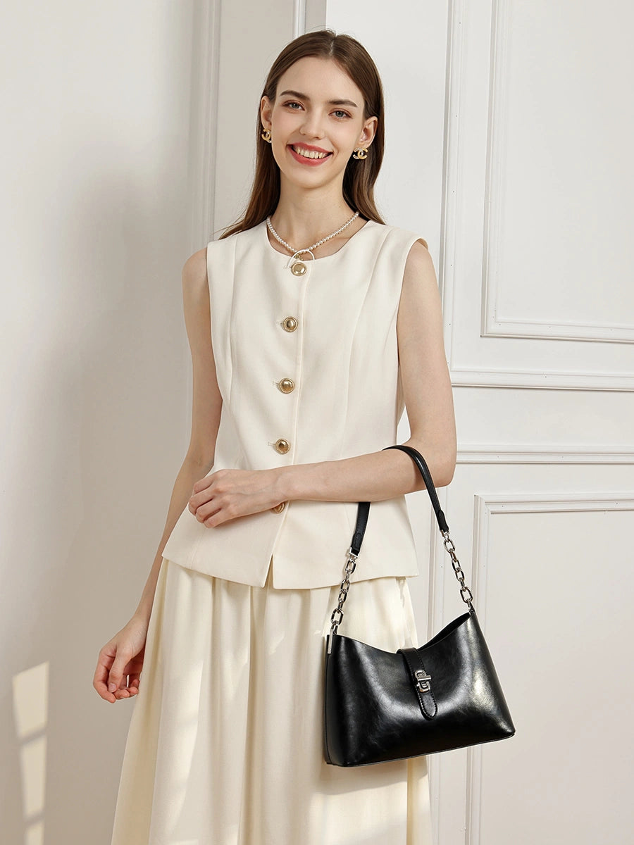 A smiling woman wearing a white outfit with the Cuirae black genuine leather handbag on her shoulder.