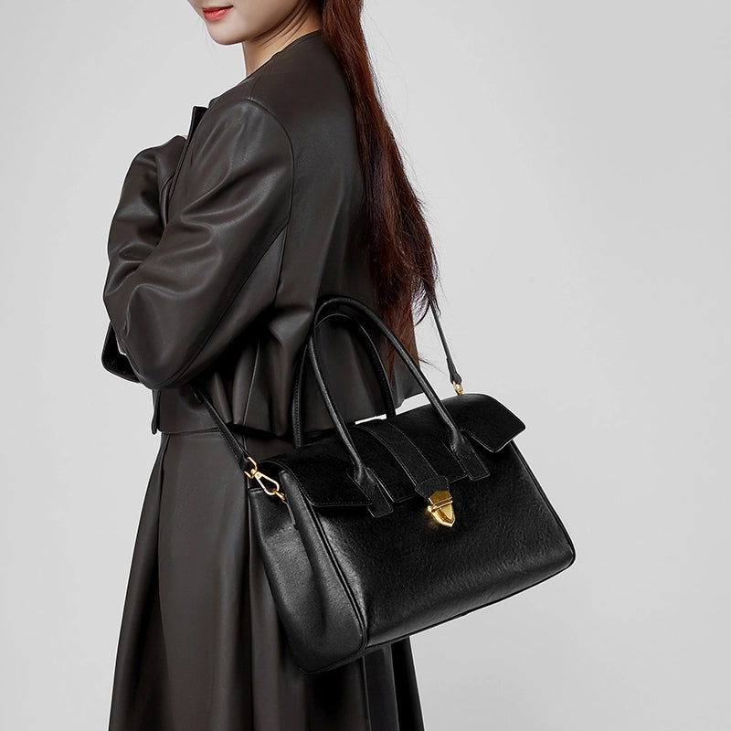 Woman wearing Cuirae black genuine leather satchel bag crossbody style, side view with gold hardware details