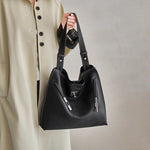 Cuirae black genuine leather tote bag with top handles and adjustable shoulder strap, handheld front closeup