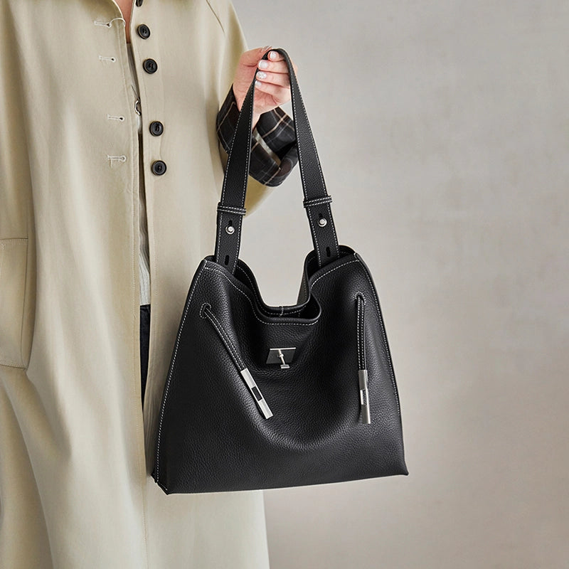 Cuirae black genuine leather tote bag with top handles and adjustable shoulder strap, handheld front closeup