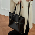 Model holding Cuirae black genuine leather tote bag, side view showing spacious interior and adjustable top handles