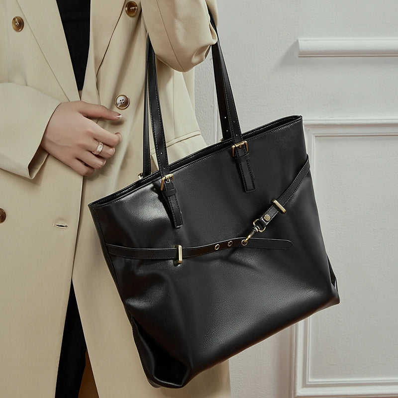 Woman wearing Cuirae black genuine leather tote bag on shoulder, angled view highlighting smooth leather texture
