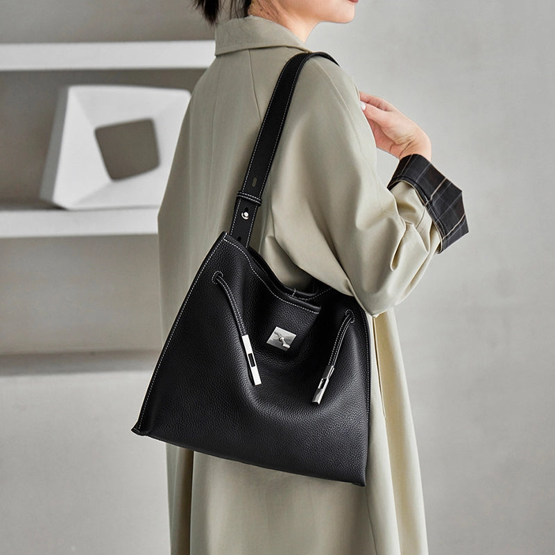 Woman wearing Cuirae black genuine leather tote  bag on shoulder, side view with silver zipper details