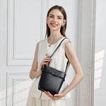 Model wearing Cuirae black leather bucket bag crossbody, front view with white sleeveless vest outfit