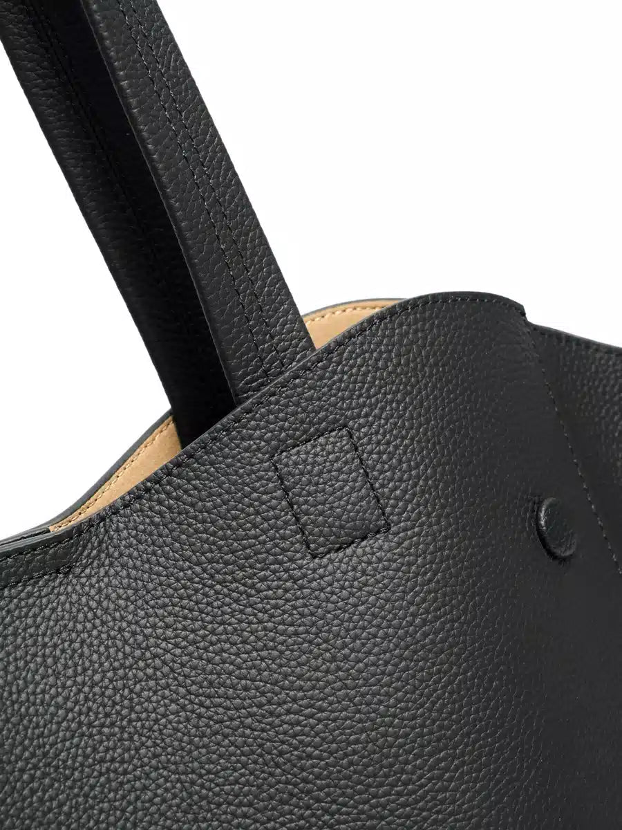 Close-up of the leather shoulder handle and stitching on a black tote