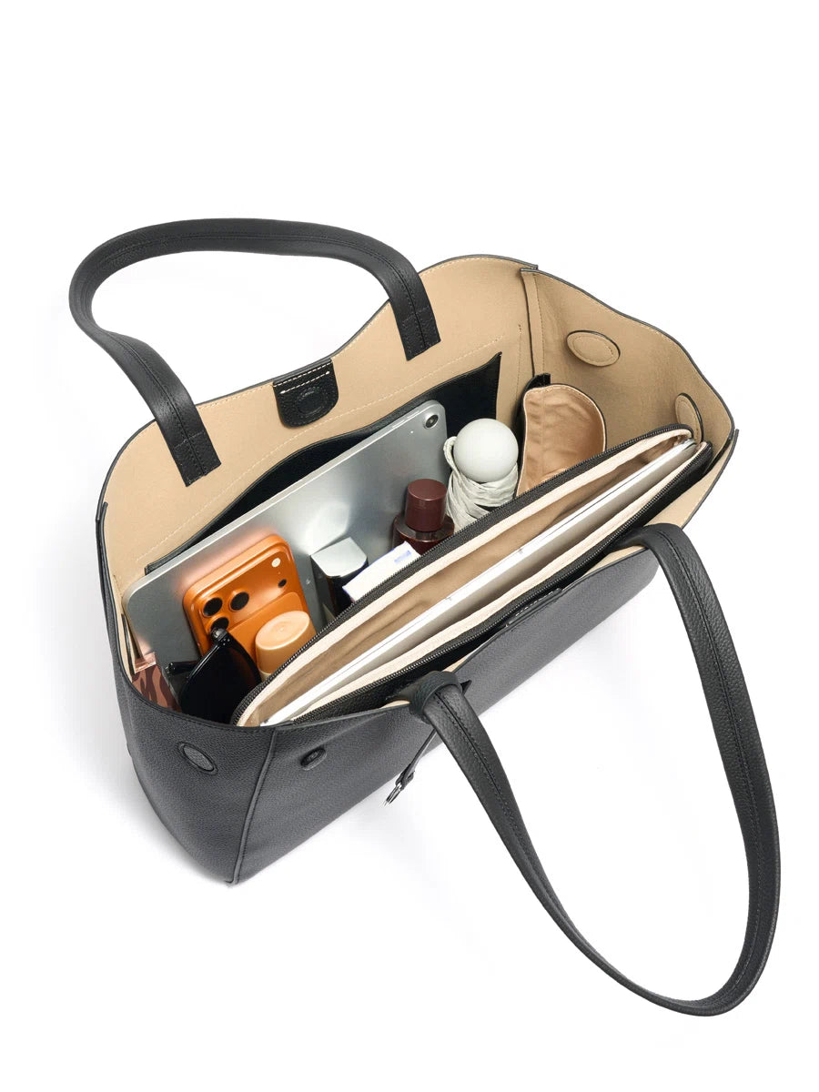 Interior of a black leather tote holding a tablet, phone, umbrella, and everyday essentials