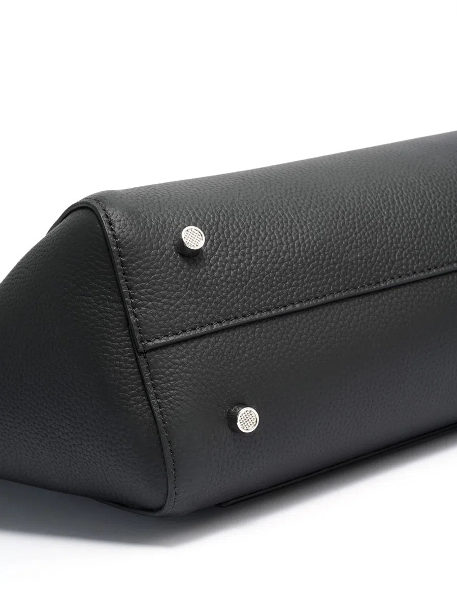 Close-up of metal feet and stitching on the base of a black leather tote