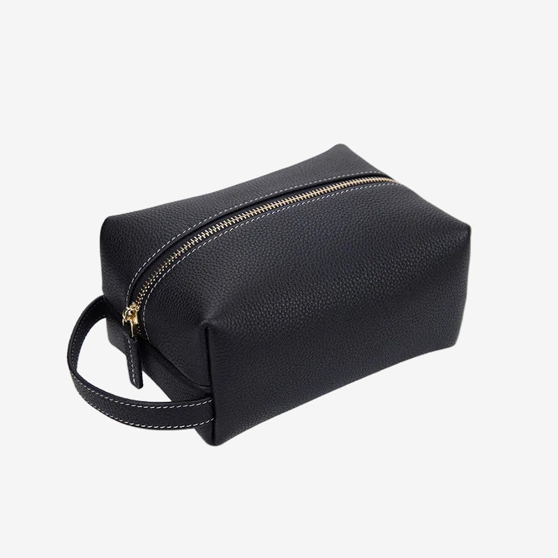 Cuirae black pebbled genuine leather makeup bag with gold zipper and wrist strap, front angled view on white background