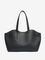 Model holding Cuirae black pebbled genuine leather tote bag by its long handles, front view showing silver ring charm