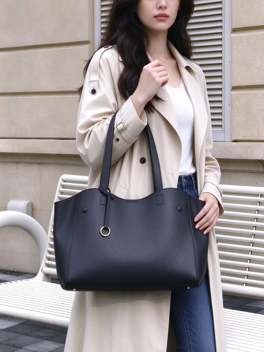 Model carrying Cuirae black pebbled genuine leather tote bag on her forearm with one hand resting on the bag, front view