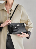 Closeup of model holding Cuirae black pebbled leather crossbody bag, showing detachable coin purse and silver hardware