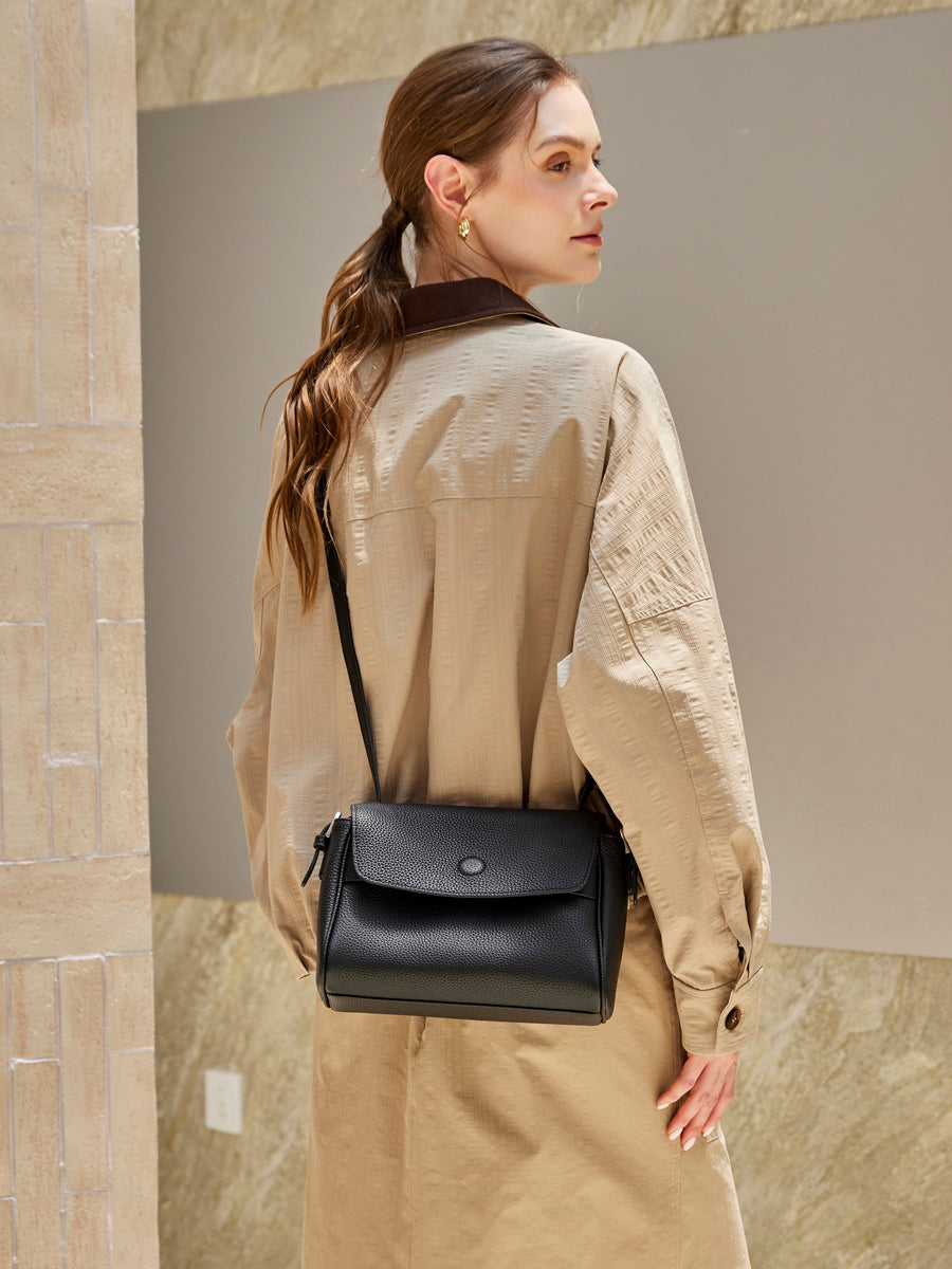 Model wearing the Cuirae black pebbled leather flap crossbody bag, rear view