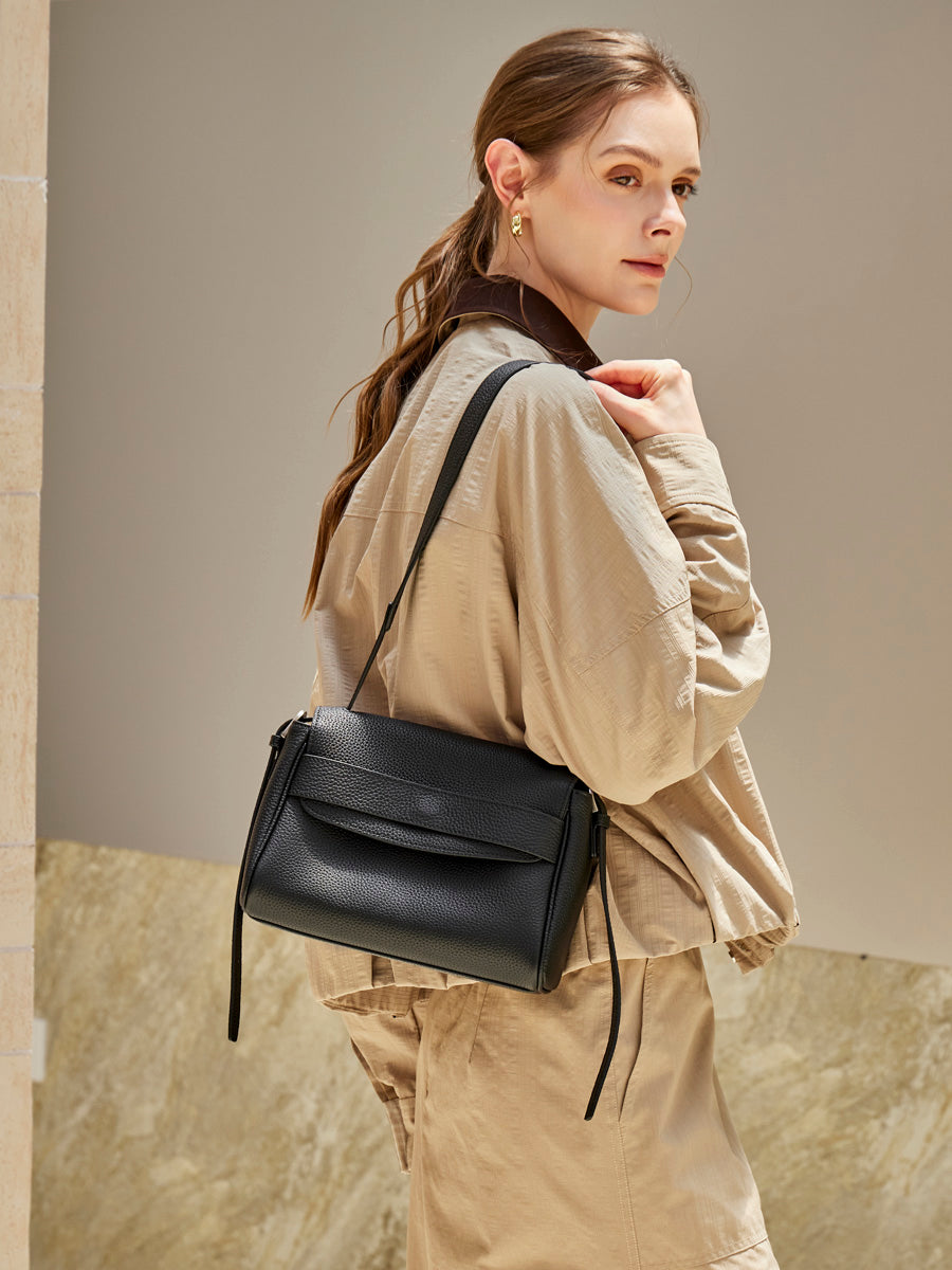 Model wearing the Cuirae black pebbled leather flap shoulder bag, rear three-quarter view