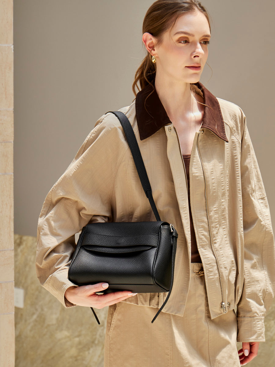 Model carrying the Cuirae black pebbled leather flap shoulder bag