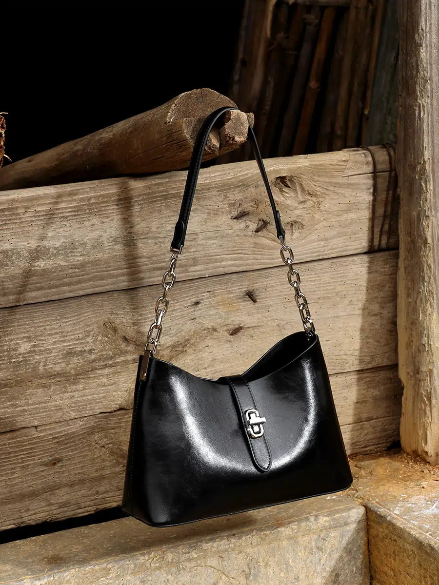 A Cuirae black top grain cowhide handbag hanging on a piece of wood outside.