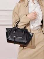 A woman in a beige outfit holding the Cuirae black top grain cowhide handbag on her arm.