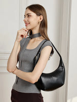A smiling woman in a grey top wearing the Cuirae black top grain cowhide handbag on her shoulder.