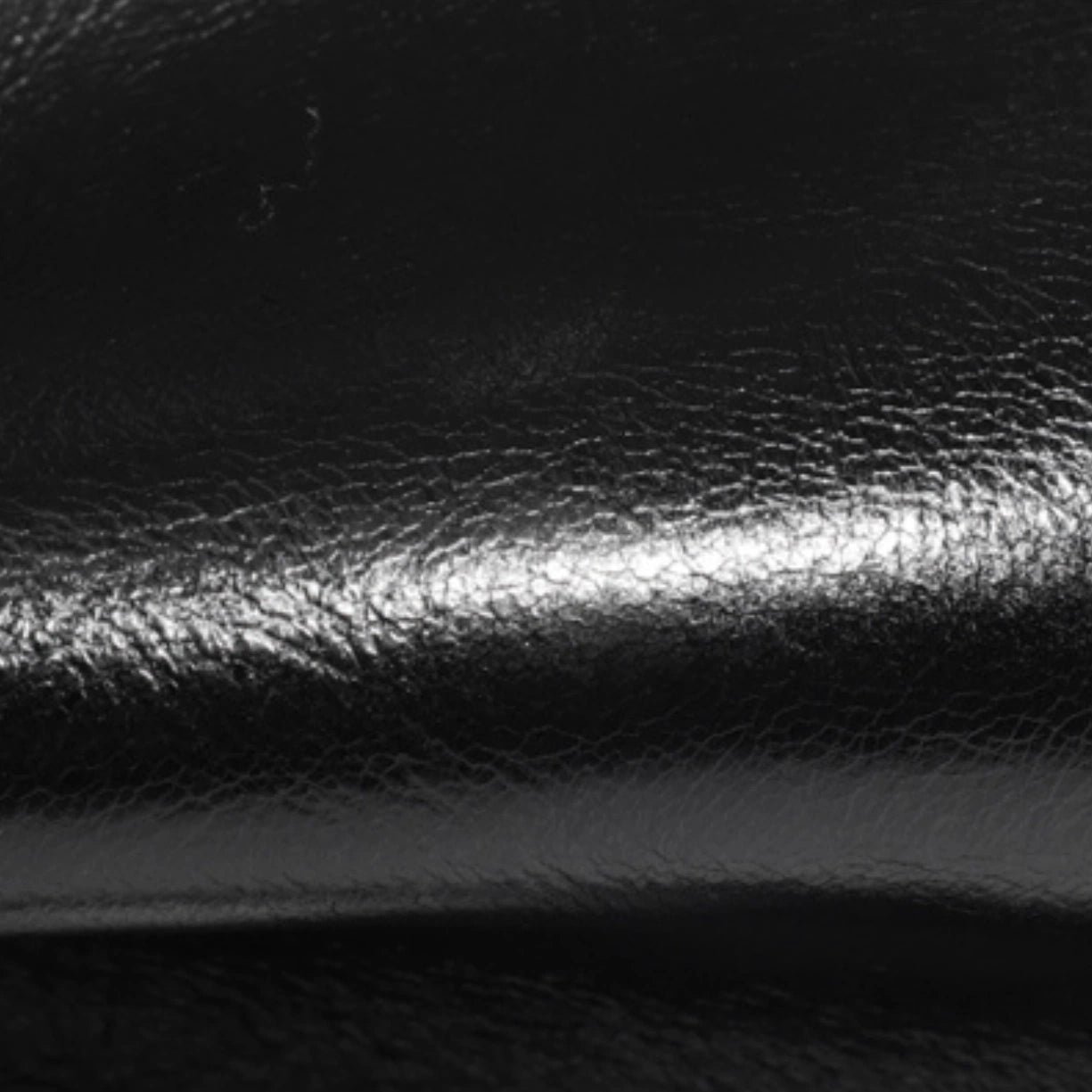 Close up of the smooth black top grain cowhide texture on the Cuirae bag.