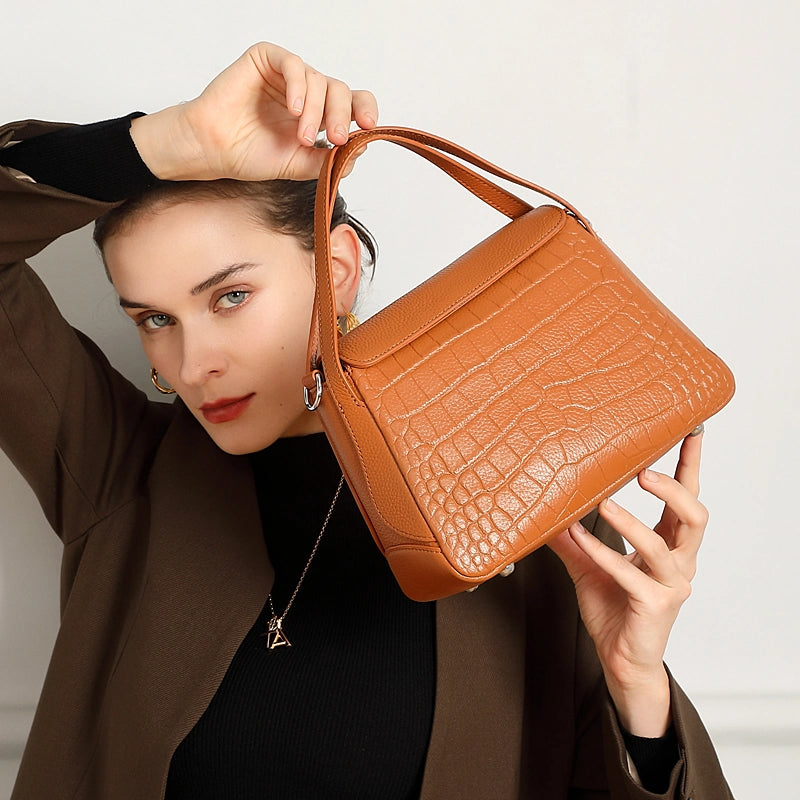 Cuirae brown crocodile embossed genuine leather crossbody bag held by model, closeup showing textured flap and silver hardware