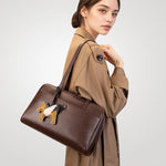 Woman wearing Cuirae brown genuine leather bowling bag on shoulder, angled view with pony charm detail
