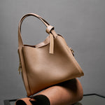 Cuirae brown genuine leather handbag resting on leather roll, side view showing soft pebbled leather texture
