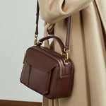 Woman wearing Cuirae  brown genuine leather  crossbody bag on shoulder, side view with top handle