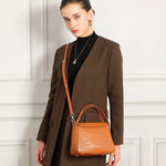 Cuirae brown genuine leather crossbody bag worn crossbody by model, showing adjustable strap and classic design