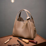 Cuirae brown genuine leather handbag on workbench with leather tools, front view highlighting premium handcrafted quality