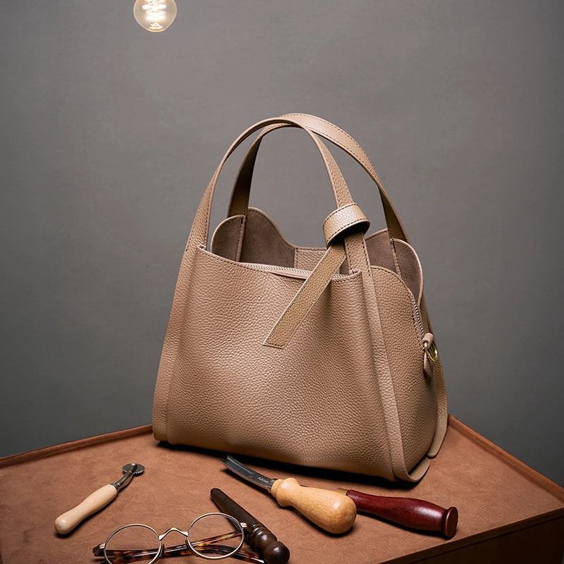 Cuirae brown genuine leather handbag on workbench with leather tools, front view highlighting premium handcrafted quality