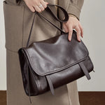 Model holding Cuirae  brown genuine leather messenger bag, closeup highlighting smooth full grain leather