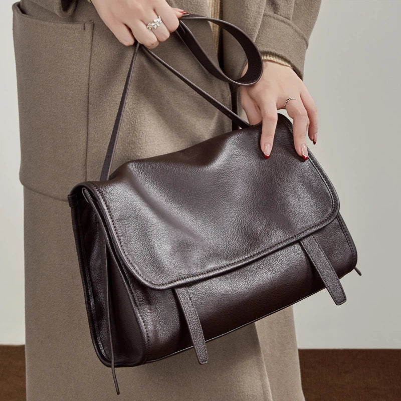 Model holding Cuirae  brown genuine leather messenger bag, closeup highlighting smooth full grain leather
