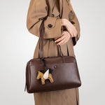 Model holding Cuirae  brown genuine leather shoulder bag by top handles, front view