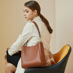 Model wearing Cuirae brown leather bucket bag on shoulder, back view with beige trench coat outfit