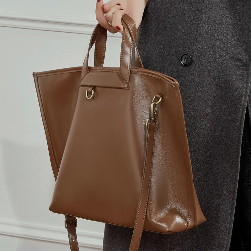 Woman carrying Cuirae brown genuine leather tote bag, front view showing spacious open-top design and gold hardware