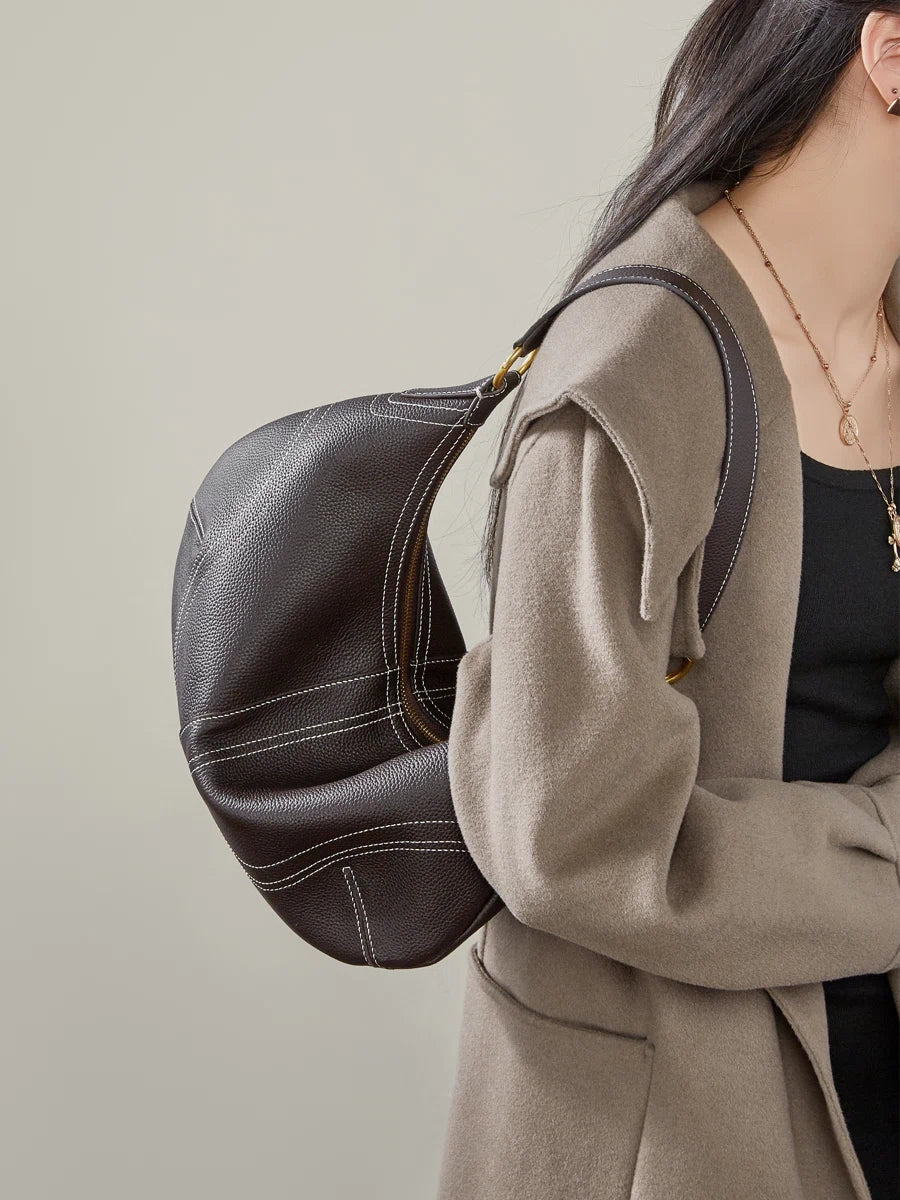 Cuirae brown pebbled genuine leather hobo bag worn under arm, side view showing contrast stitching and zipper closure