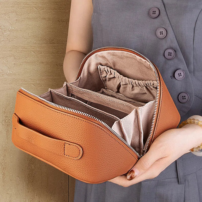 Cuirae brown pebbled genuine leather makeup bag open, showing interior compartments and lining held by model