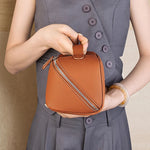 Cuirae brown pebbled genuine leather makeup bag with double zipper and top handle, front view held by the model with both hands